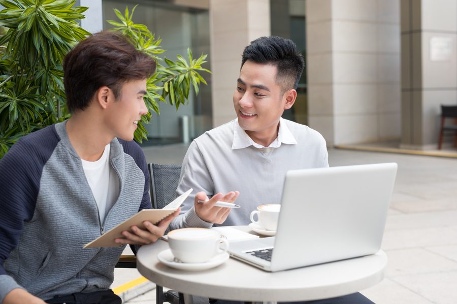 Two people talking over a laptop in a cafe